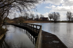 Einer der beiden Seen vor dem Park mit einer Holzbrücke